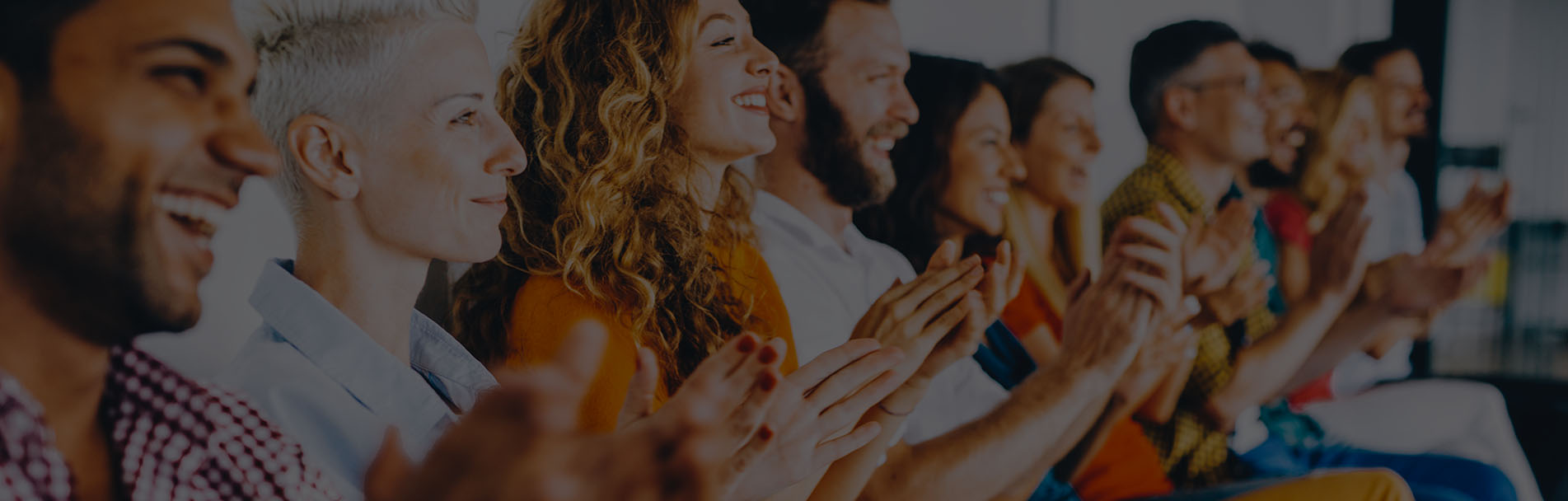 ALT Text: a Row of people smiling and capping sitting down