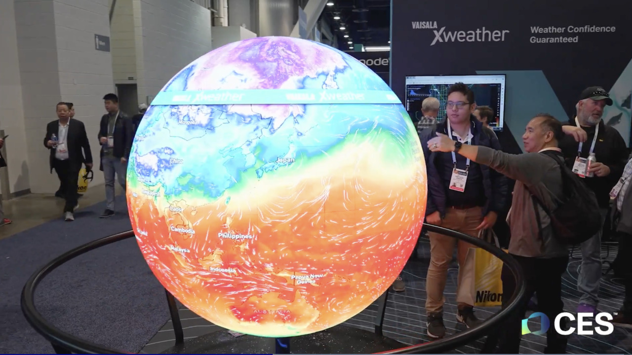 ALT Text: Attendees interact with a colorful, illuminated weather globe at the CES event