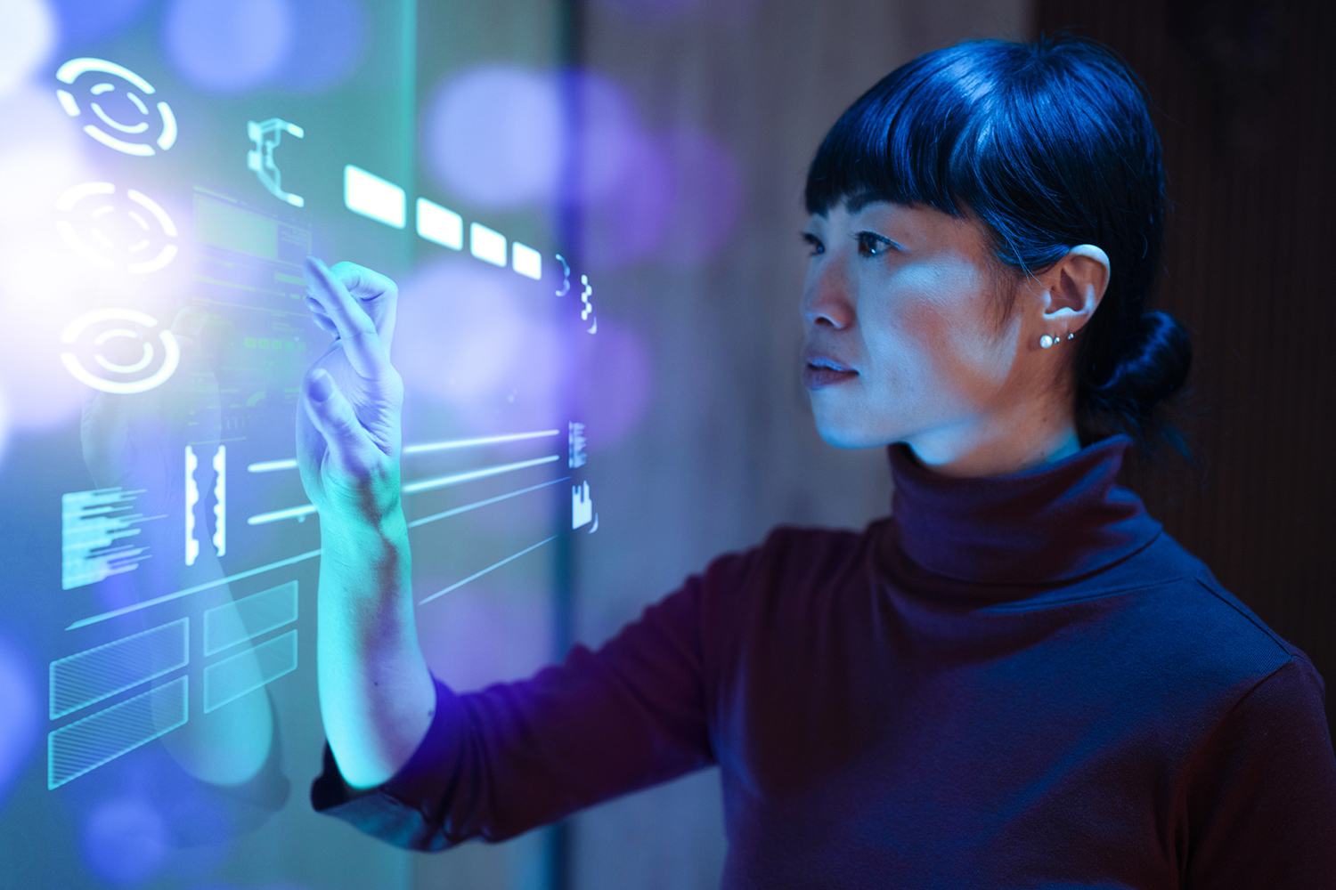 ALT Text: A person interacts with a holographic interface, touching virtual data and graphs, with a futuristic illuminated display.